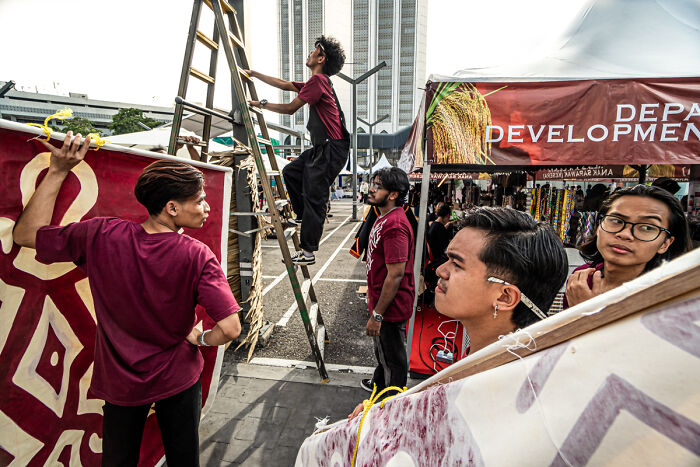 Group of young people setting up a street scene with banners and ladder in candid street photos capturing quiet beauty of everyday life
