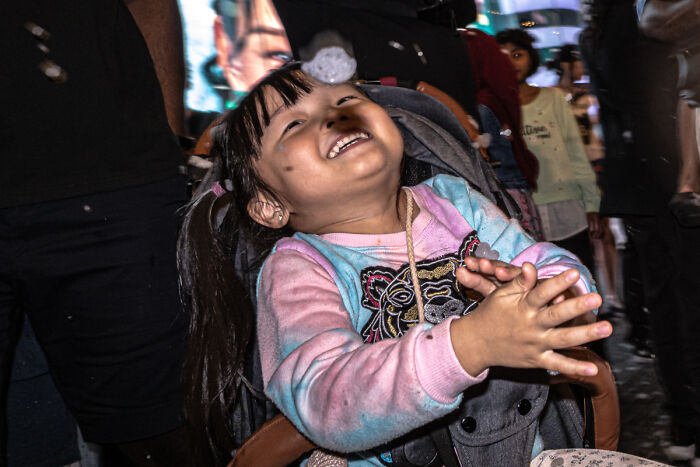 A candid street photo of a joyful child laughing and clapping, capturing the quiet beauty of everyday life.
