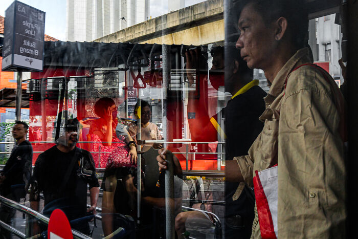 Candid street photo showing people inside a bus with reflections capturing the quiet beauty of everyday life.