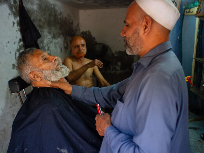 Man getting a beard trim in a candid street moment captured by a photographer full of emotion.
