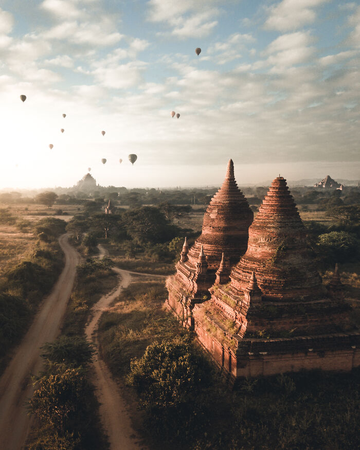 Ancient temple with hot air balloons floating over scenic landscape in breathtaking travel photos by Bored Panda community