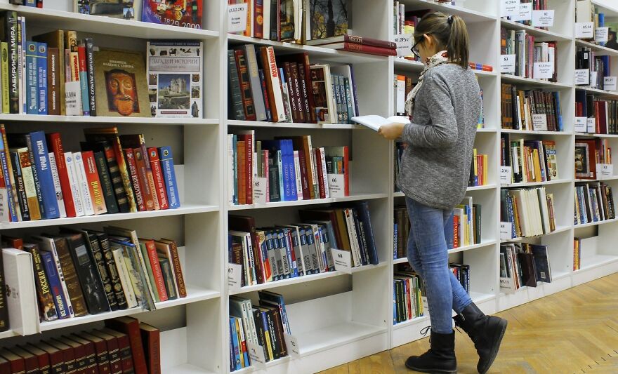 Person browsing books in library near shelves, illustrating a then vs now poll concept comparing past and present.