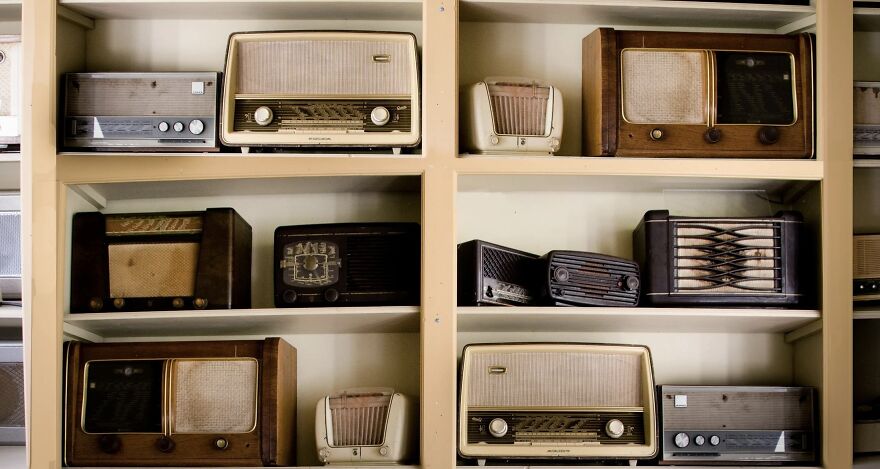 Collection of vintage radios displayed on white shelves showcasing the then vs. now poll concept.