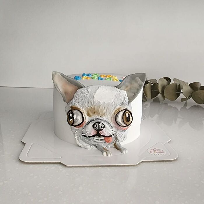 Pet-themed cake shaped like a white dog with large eyes and realistic texture capturing unique personality details.