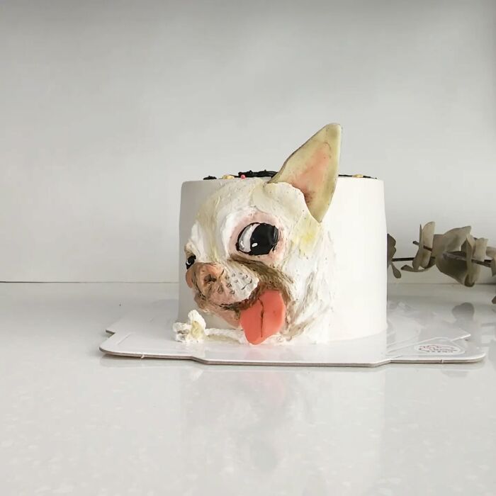 Pet-themed cake featuring a detailed dog face with tongue out, showcasing the artist's skill in capturing unique pet personality.
