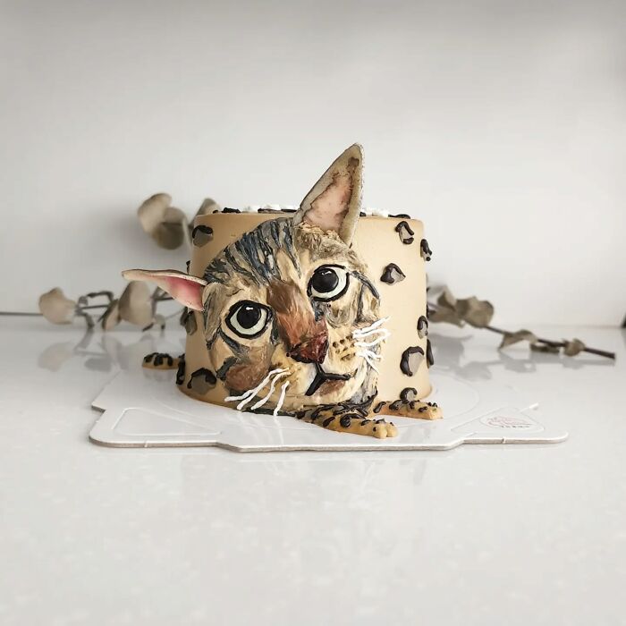 Pet-themed cake featuring a realistic cat face with detailed fur and expressive eyes, showcasing adorable edible art.