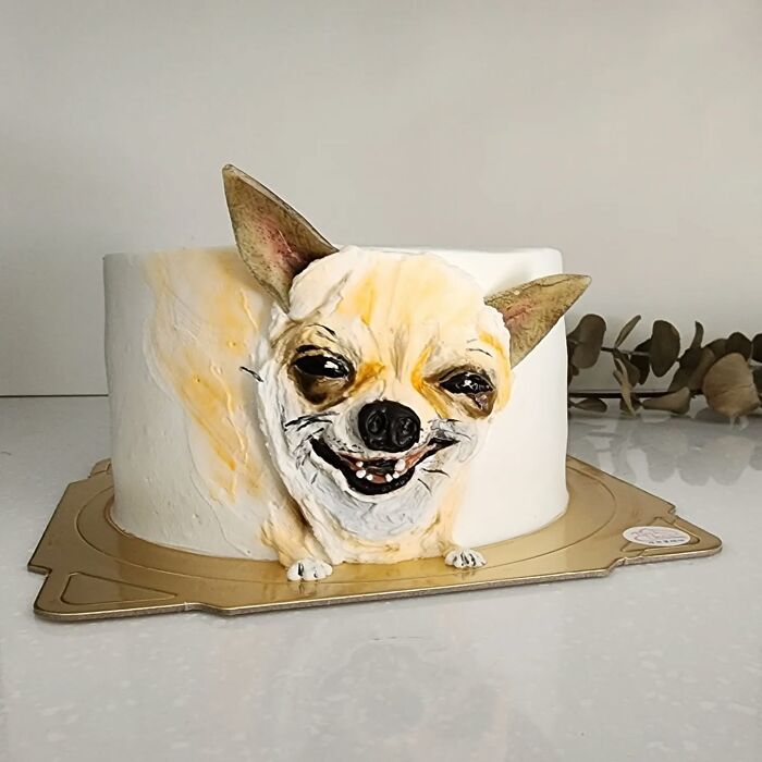 Realistic pet-themed cake shaped like a smiling dog, showcasing the artist’s skill in capturing unique pet personality.