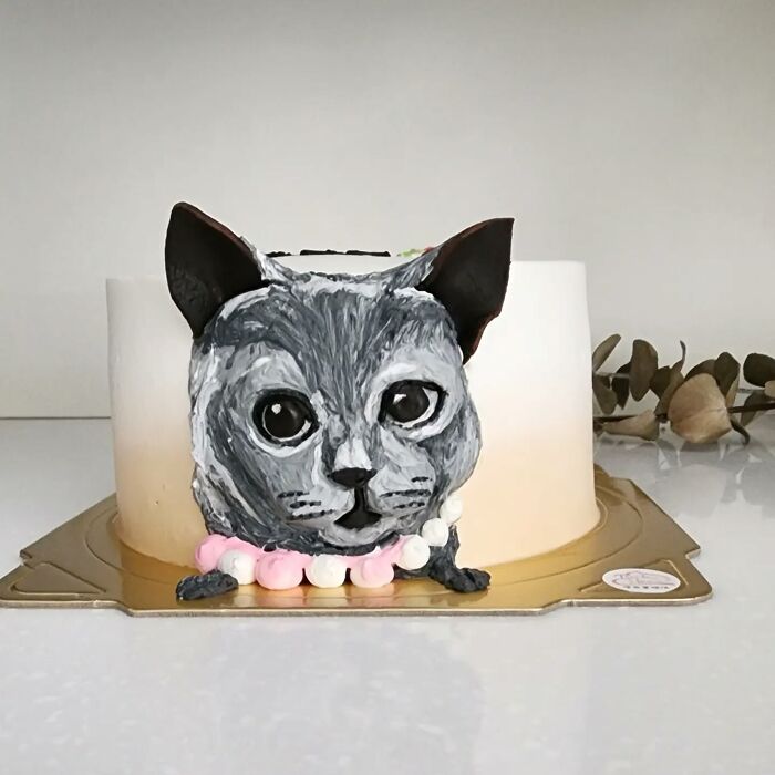Pet-themed cake featuring a detailed cat face, showcasing the artist's skill in capturing pet personality in cake art.