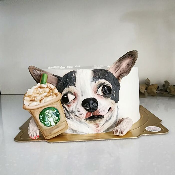 Realistic pet-themed cake shaped like a dog holding a detailed Starbucks drink, showcasing adorable edible art capturing pet personality.