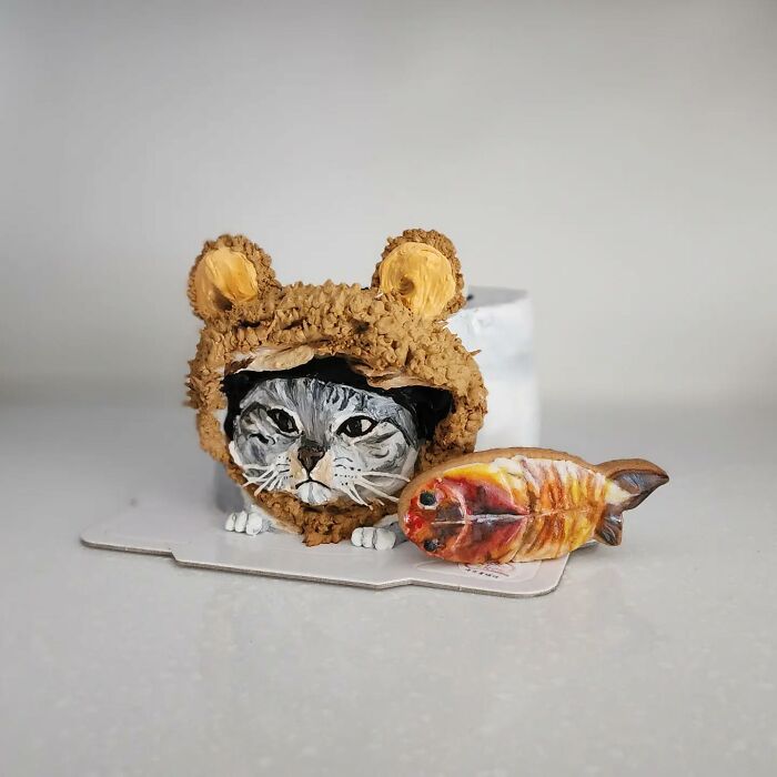 Cat-themed adorable pet cake wearing a bear hat with a fish-shaped cookie, showcasing unique pet personality in cake art.