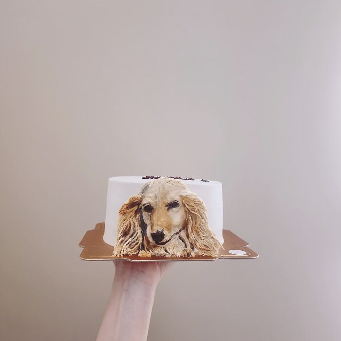 Hand holding a pet-themed cake with a detailed dog portrait, showcasing an artist's adorable pet-themed cake design.