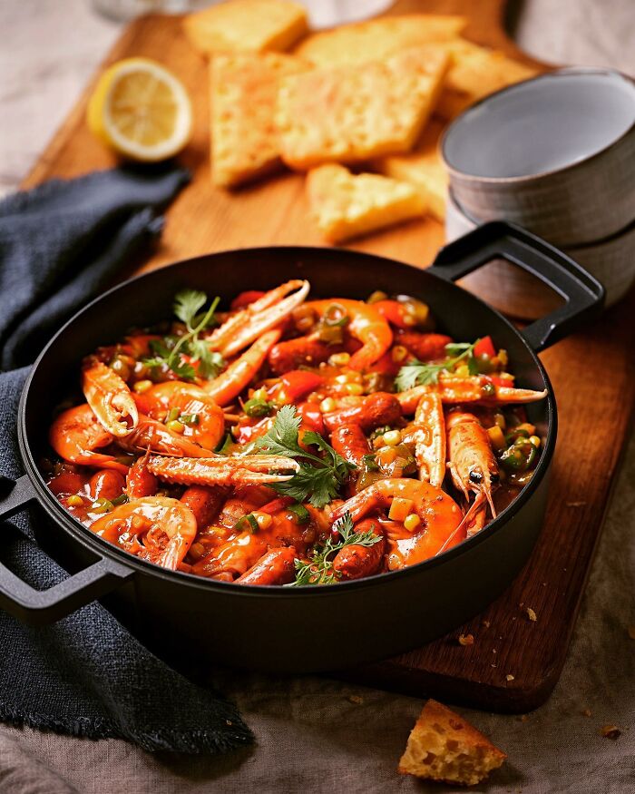 Seafood stew with shrimp and vegetables served in a pan, styled for mouthwatering food photos by Kai Stiepel.
