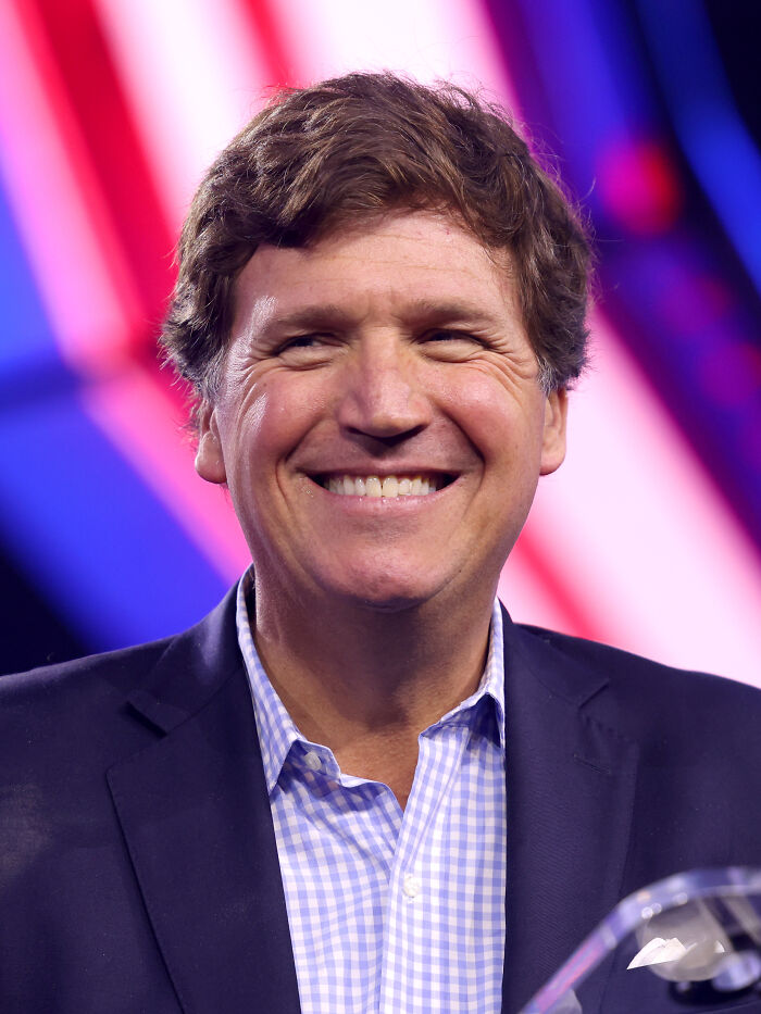 Smiling man in a blazer and checkered shirt with colorful blurred background, representing private resort worker AMA.