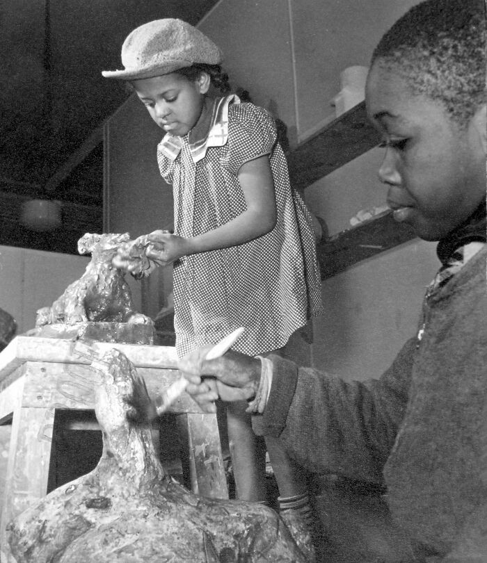 Young Black artists working on sculptures in a studio during crucial moments that defined the Harlem Renaissance.