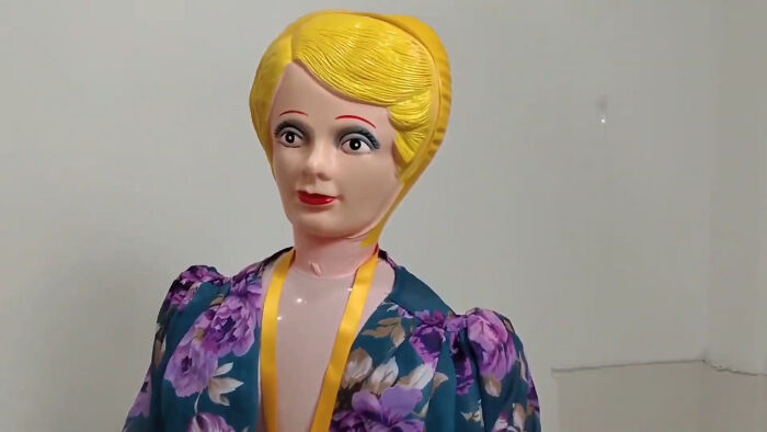 Vintage plastic doll with yellow hair wearing a floral dress, evoking creepy and scary moments from truck drivers.