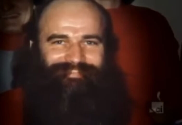 Bearded man with intense gaze in a dimly lit setting, related to scary and unsettling Wikipedia articles.