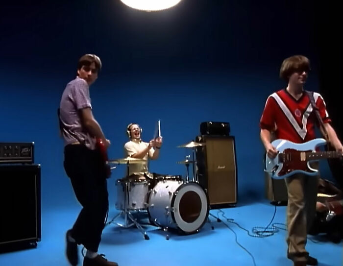 Three musicians performing with guitars and drums in a studio setting capturing best moments of being there when written.