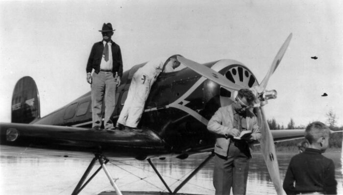 Black and white photo showing men inspecting an old airplane, one wearing a hat, with the main SEO keyword famous people.