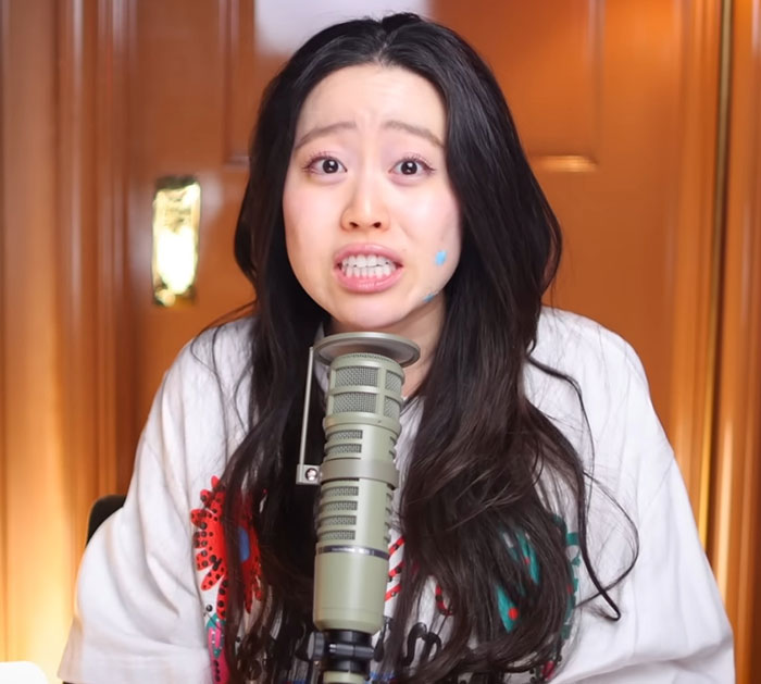 Woman with long dark hair speaking into a microphone, revealing Diddy's aged look in court during trial discussion.