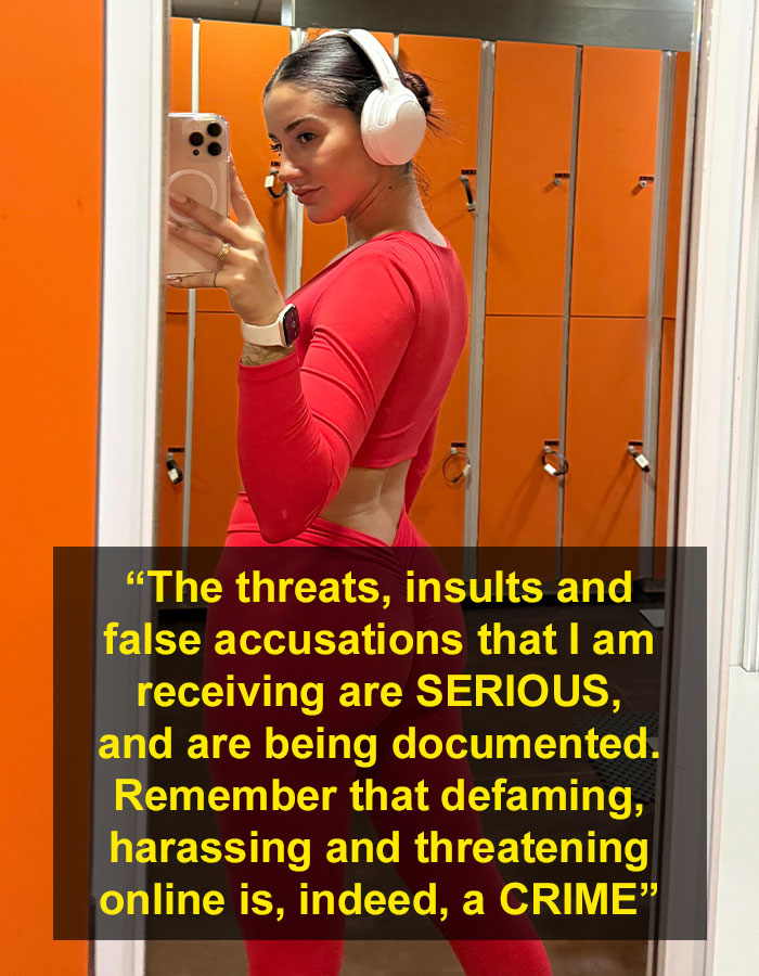 Influencer wearing red workout outfit and headphones taking a mirror selfie amid online harassment backlash.