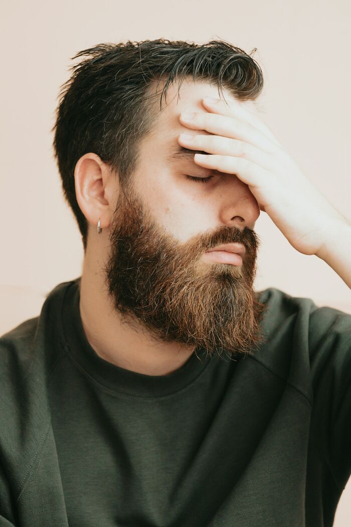Young bearded man looking stressed and frustrated, reflecting on the consequences after hooking up with a friend's parent