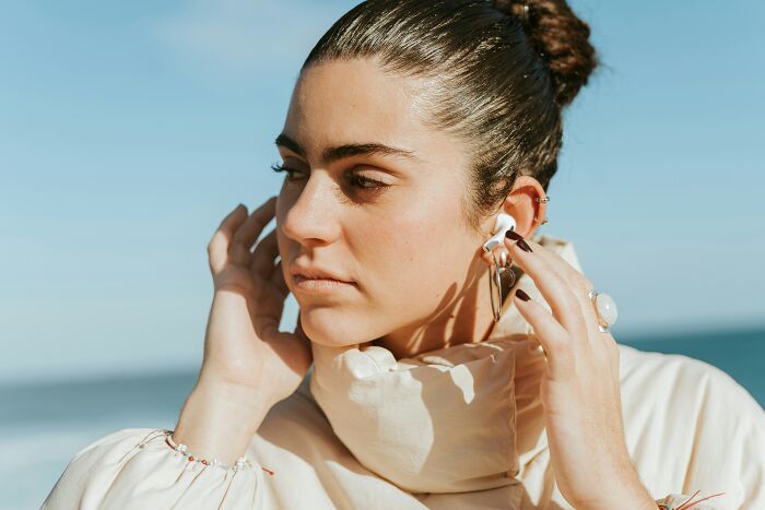 Young woman adjusting earbuds outdoors, reflecting a calm moment related to postpartum OCD awareness and experiences.