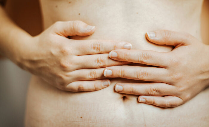 Close-up of hands pressing on a bare abdomen, illustrating shocking discoveries made during autopsies by doctors.