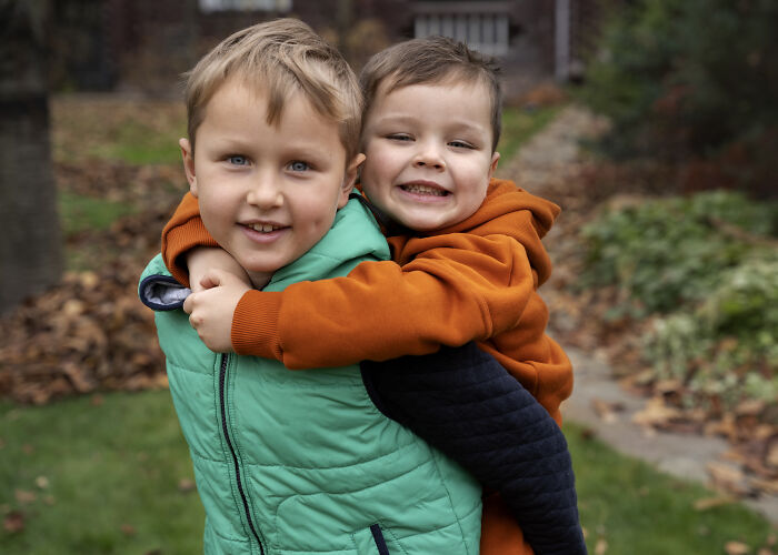 Two young boys outdoors, one giving the other a piggyback, illustrating unique and acceptable baby names.