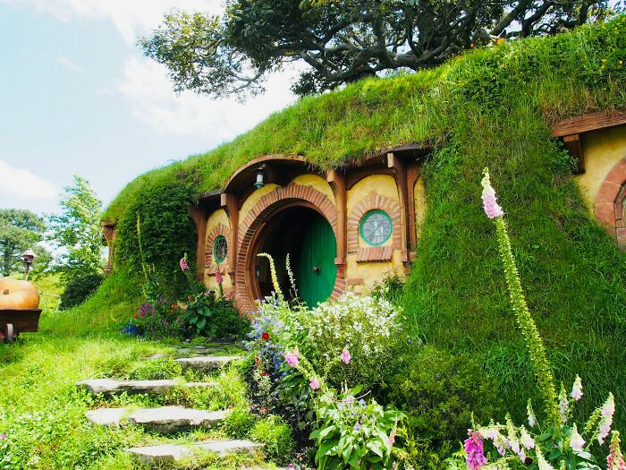 Hobbit-style house with round door and windows surrounded by greenery in a travel destination tourists say to avoid.