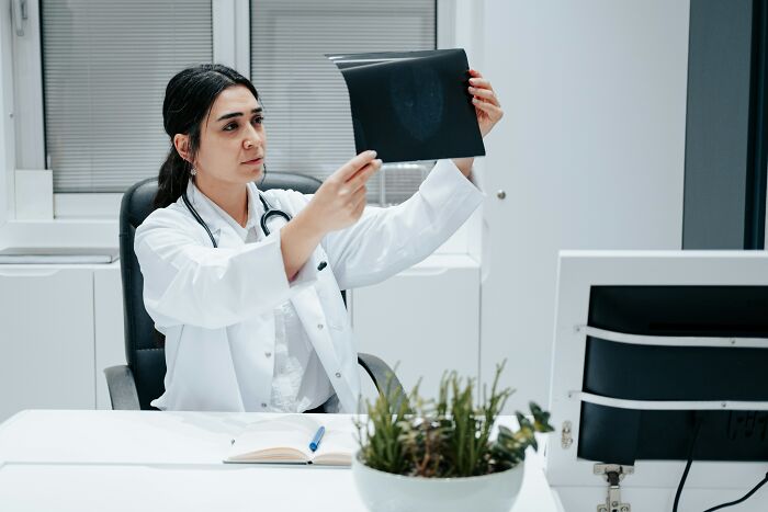 Female doctor in white coat examining medical scan, illustrating shocking discoveries made during autopsies in clinical setting
