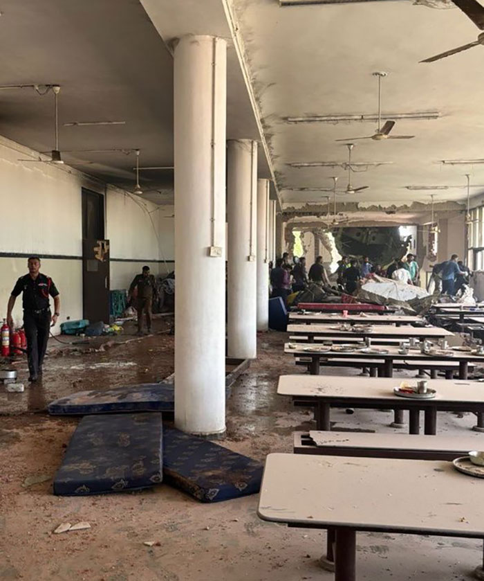 Damaged Air India Boeing jet crash site with rescue workers amid debris and disturbed indoor seating area.