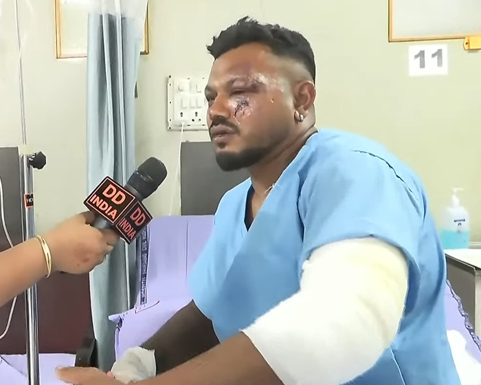 Injured man in hospital gown being interviewed, related to Air India pilot hero in tragic crash rescue.
