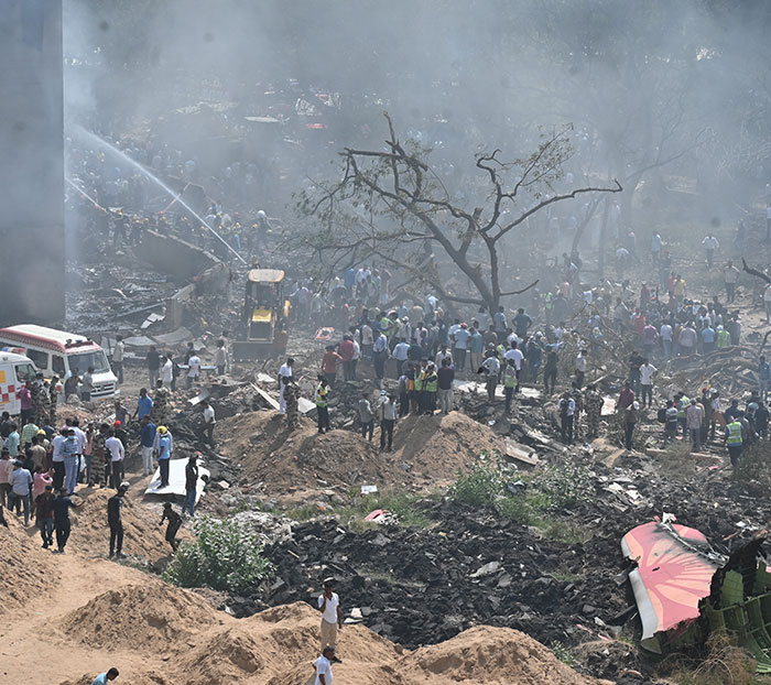 Rescue teams and crowds working amid debris and smoke at the Air India plane crash disaster site.