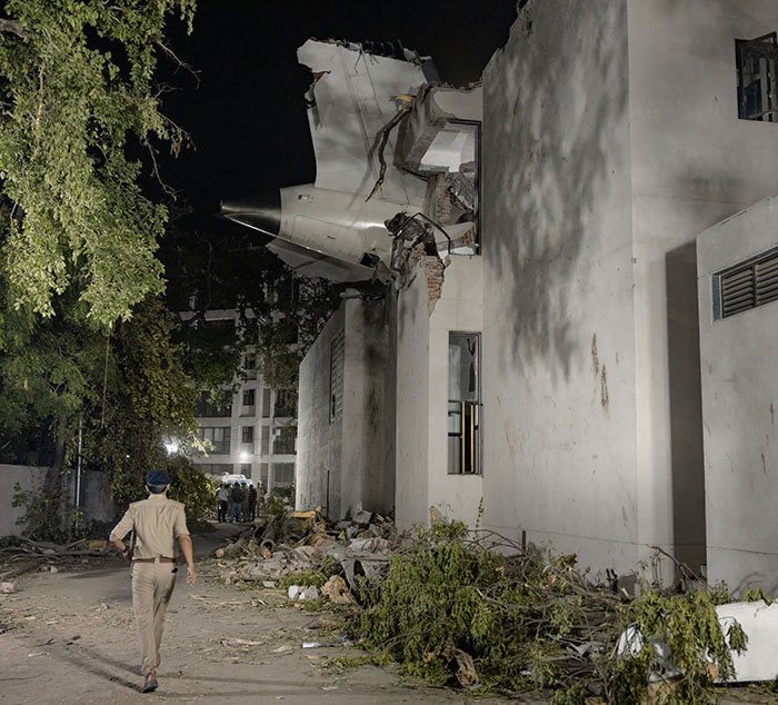 Air India plane wreckage embedded in building after disaster, with police officer inspecting the final moment captured site.