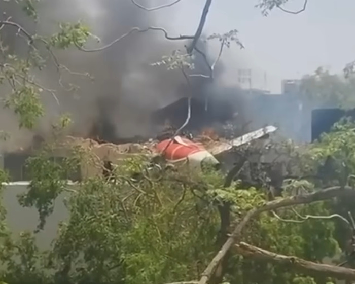 Smoke rising from wreckage of Air India crash site surrounded by trees after sole survivor's heartbreaking act for brother