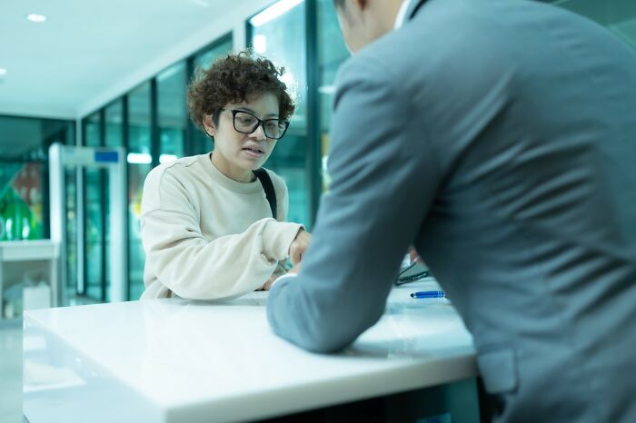 Woman explaining items to airport security officer at a counter, highlighting unexpected airport security challenges.