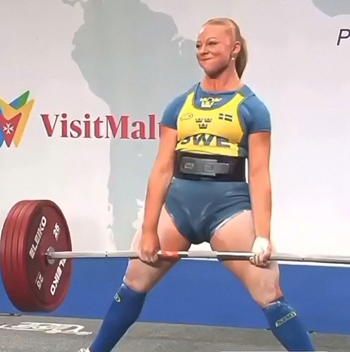 Woman powerlifting during competition, lifting heavy barbell, moment from viral video sparking internet debate on unusual incident. Woman powerlifting during competition, lifting heavy barbell, moment from viral video sparking internet debate on unusual incident.