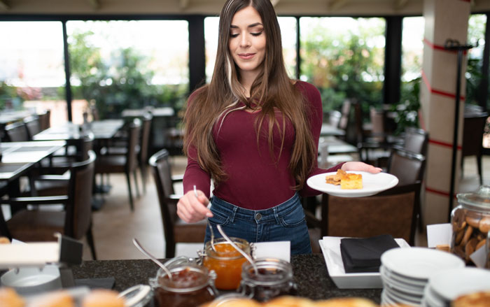 Woman solo traveler serving food at buffet counter, with entitlement expectation about alcohol behavior around kids.