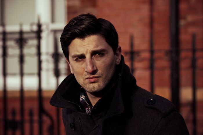 Young man in a dark coat standing outside, reflecting on cultural big no no to do in different countries.