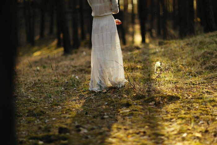 Woman in a white dress standing in a sunlit forest, evoking creepy and scary moments from truck drivers’ lives.