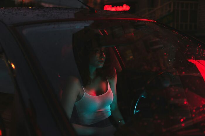 Person sitting alone in a dark car at night, reflecting on moments of realizing a close friend was a total jerk.