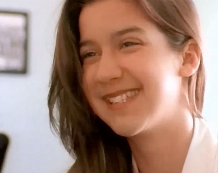 Young former Hollywood star smiling warmly, reflecting on life after giving up the spotlight for a normal career.