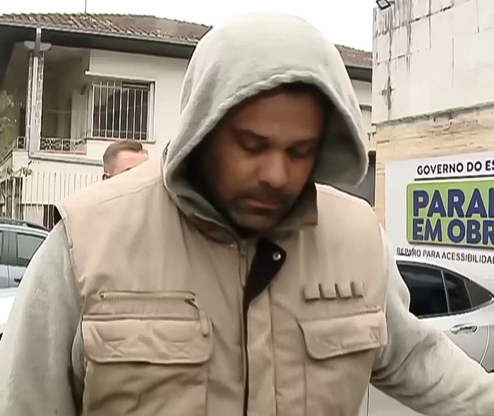 Man in beige vest and gray hoodie looking down, related to beauty queen strangled by family friend and former teacher case.