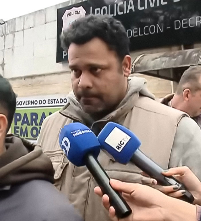 Man giving statement outside police station with multiple microphones, related to beauty queen strangled by family friend case.