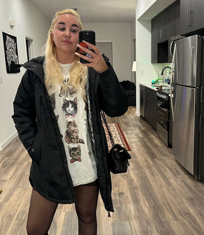 Amanda Bynes taking a mirror selfie indoors, wearing a black jacket and cat graphic shirt, related to Ozempic use news.