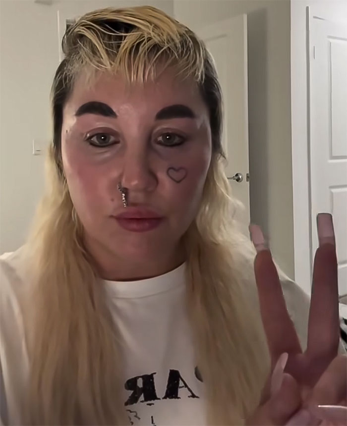 Amanda Bynes showing peace sign indoors, revealing she is using Ozempic, sparking mixed reactions online.