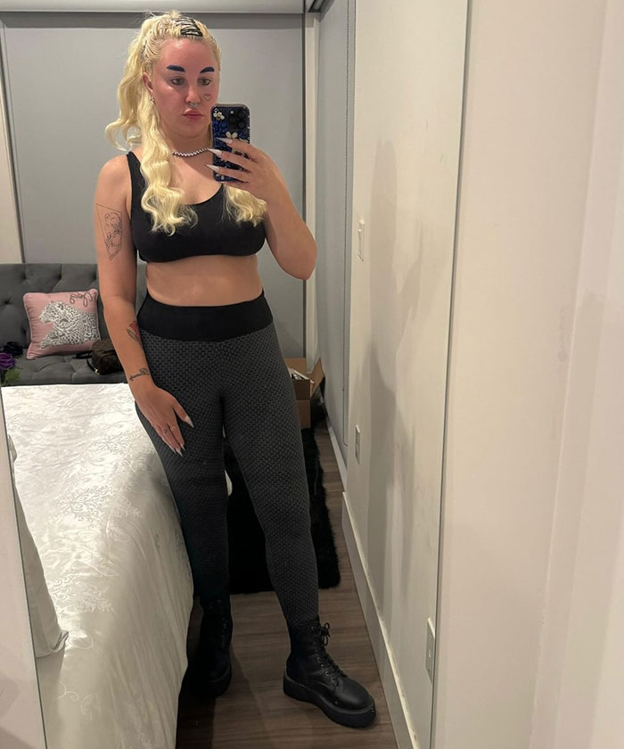 Amanda Bynes taking a mirror selfie, wearing black workout clothes, revealing her use of Ozempic and sparking mixed reactions.