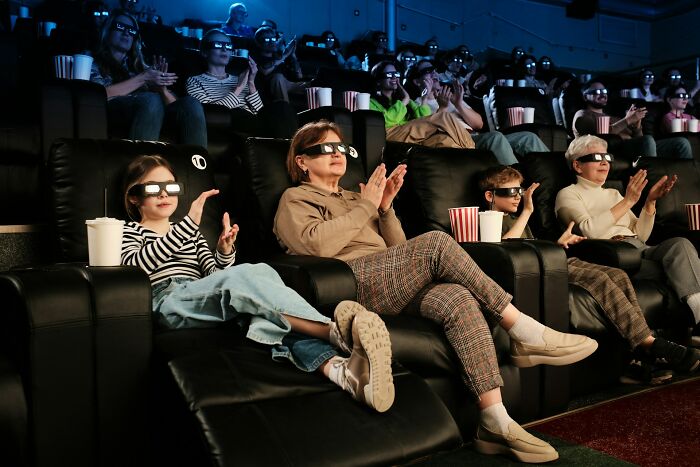 Audience of different ages wearing 3D glasses watching a movie in a theater representing industries hit by millennials.
