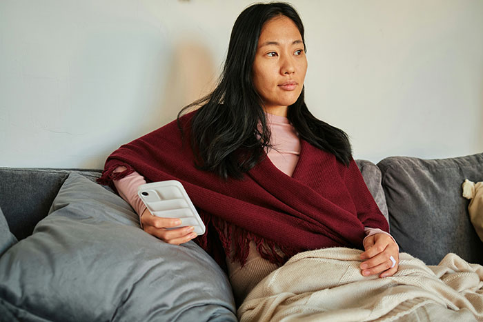 Woman wrapped in a blanket sitting on a couch, reflecting on psoriasis and body makeup issues before a wedding event.