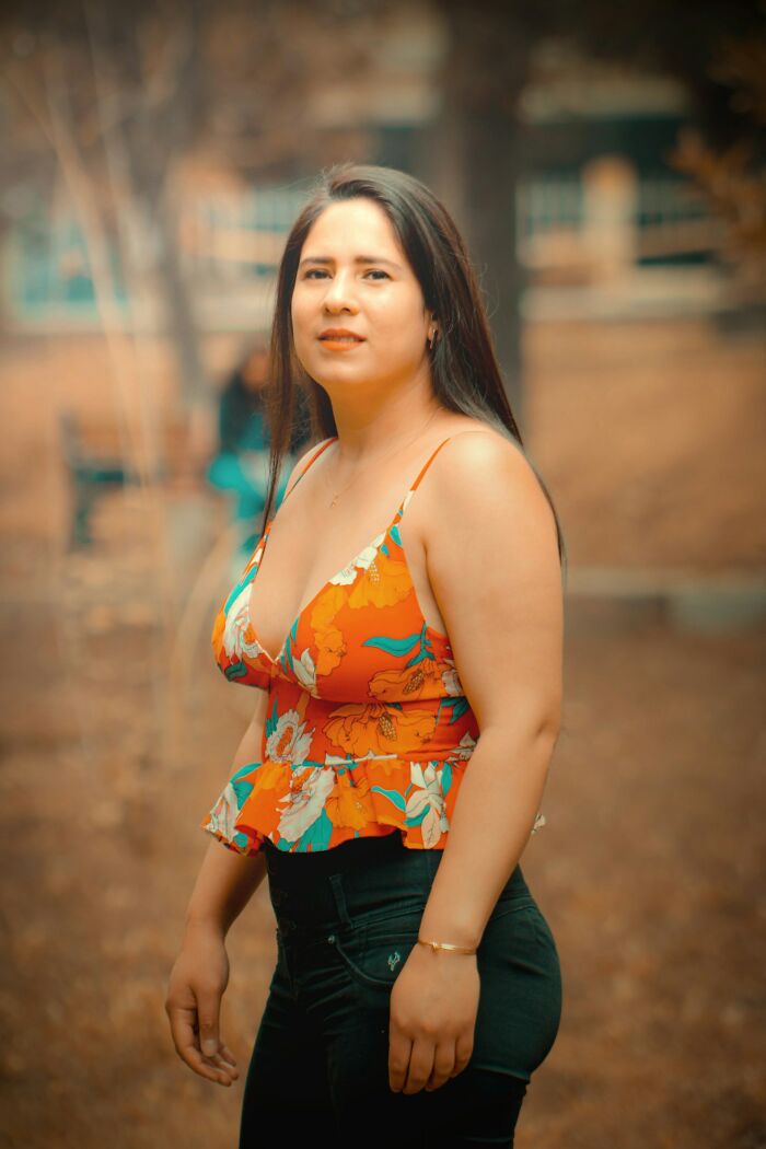 Young woman outdoors wearing a floral top, representing themes of pregnancy, childbirth, and postpartum facts.